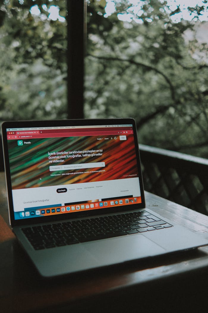 Open laptop on a wooden table with a scenic outdoor view.